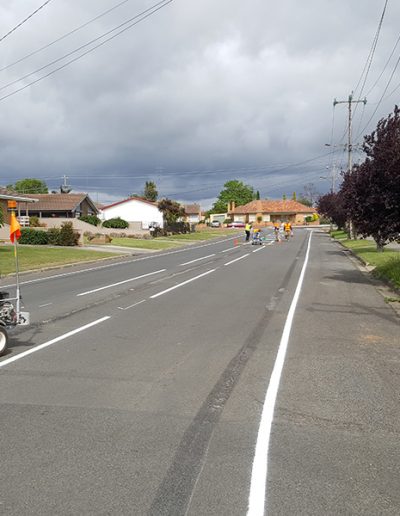New road lines being completed by the linemarking crew along the middle and side of a suburban street