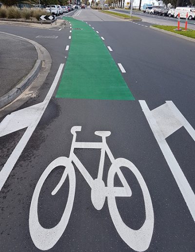 A bike lane marked showing the bike stencil and area to ride along the side of a beach road in the city.