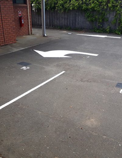 Directional arrows on the road and numbered carparks for a motel